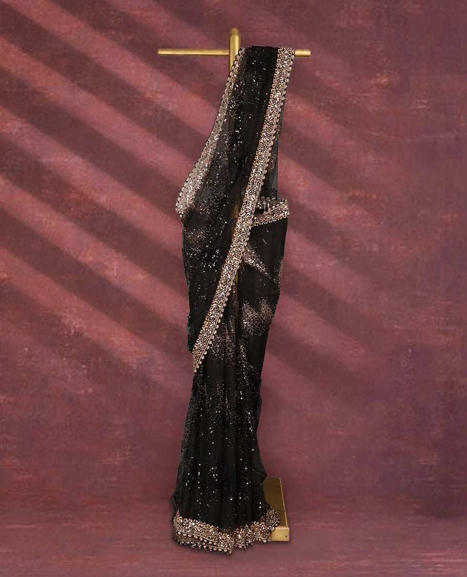 Black colour net designer saree embellished with all over shimmering sequin work in diagonal patterns and a heavily sequined border, exuding glamour and elegance, paired with a matching worked blouse for a striking look