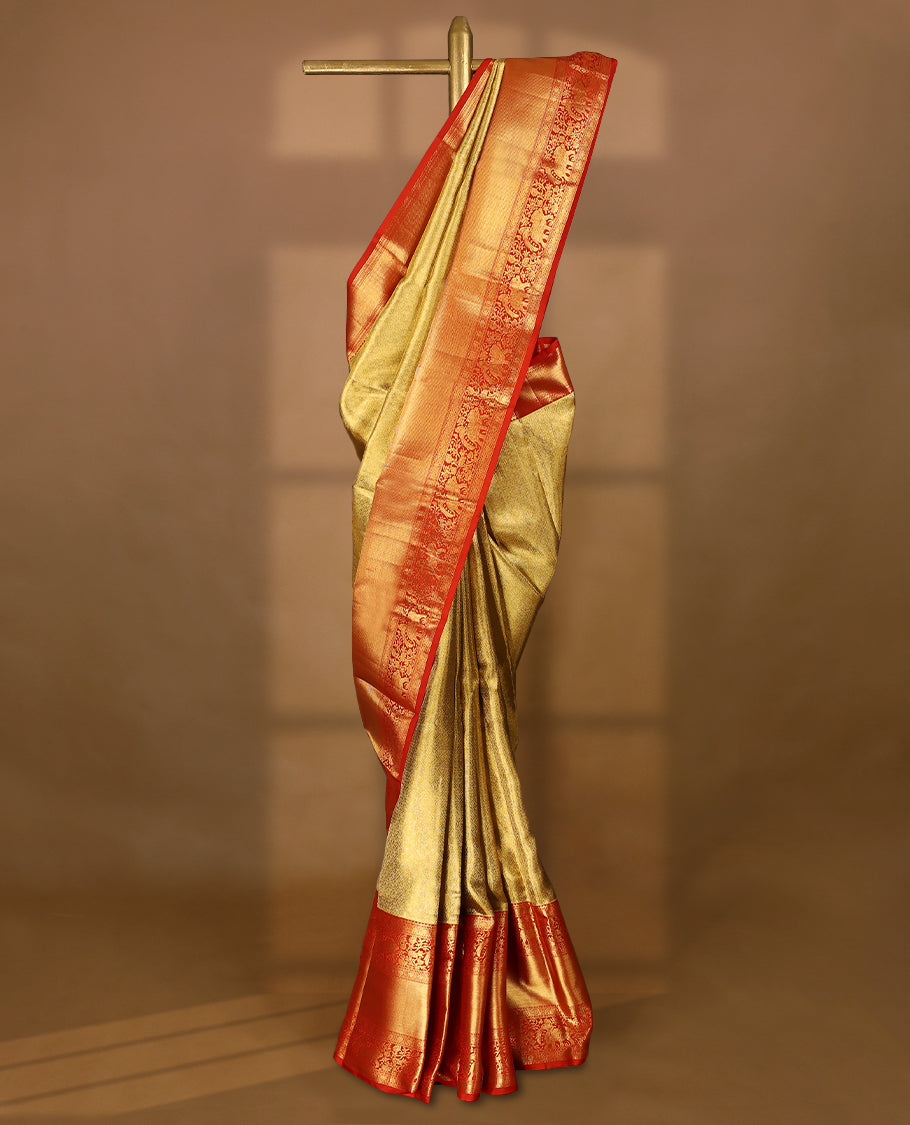 Gold Colour Kancheepuram tissue silk saree featuring an intricately woven antique zari jacquard design on the body, elegantly complemented by a bright red traditional border with elephant, bird, and Rudraksham motifs, and paired with a matching blouse.