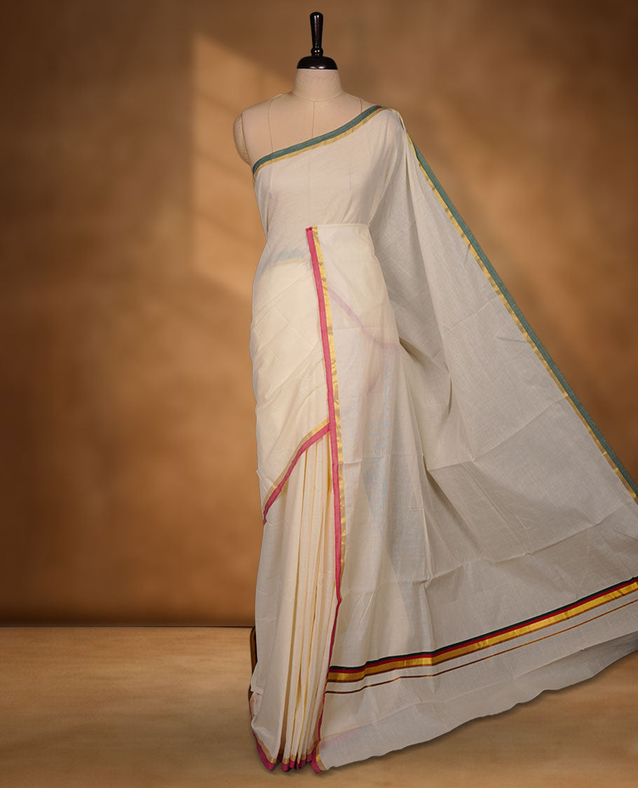 Off-white colour cotton Kerala saree featuring a classic gold kasavu border, accentuated with subtle green and pink contrast edging, a plain elegant body, and paired with a matching blouse.