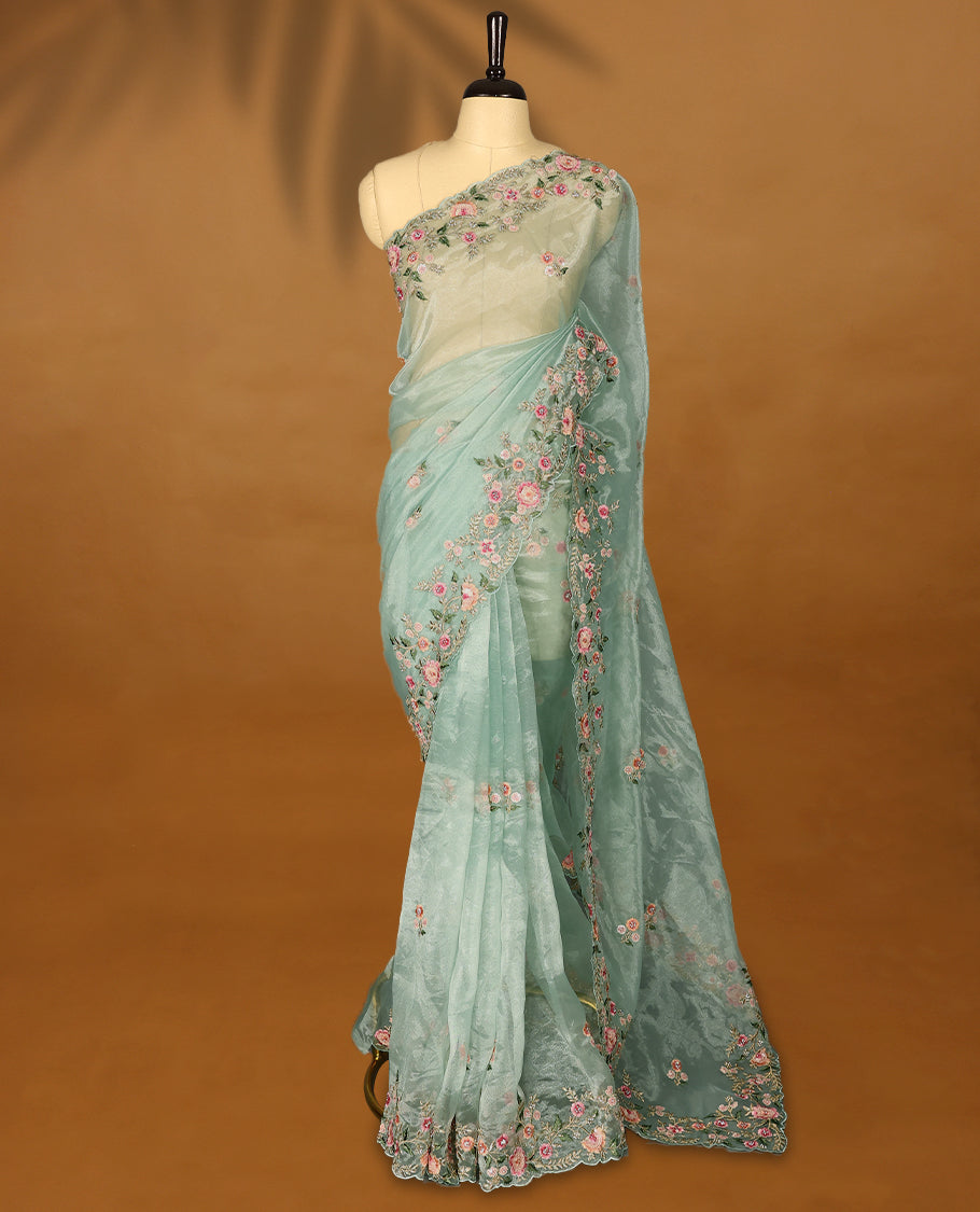Pastel Aqua Organza Tissue Silk Saree is beautifully adorned with intricate pink floral embroidery Border and a matching blouse.
