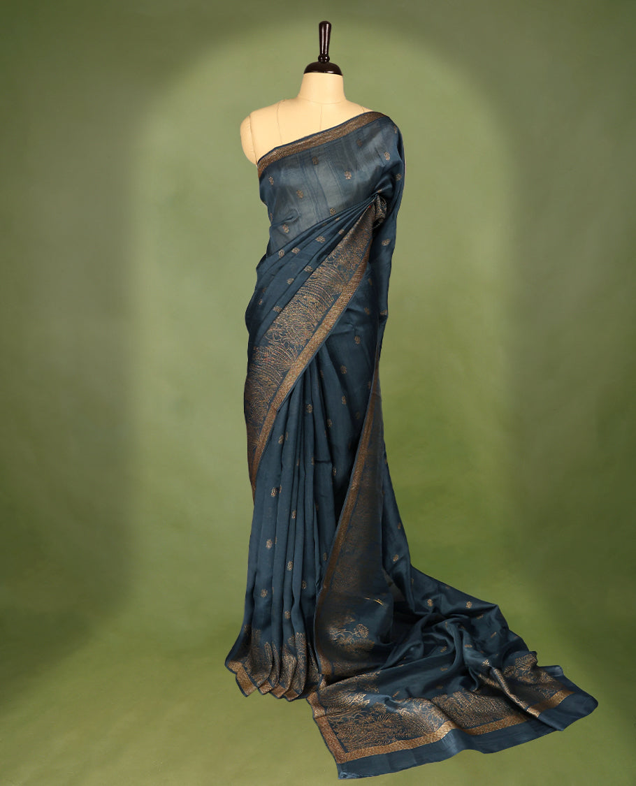 German blue semi-Banaras tussar georgette saree adorned with antique zari floral motifs on the body, beautifully highlighted with a pencil art garden-inspired border, paired with a matching blouse.