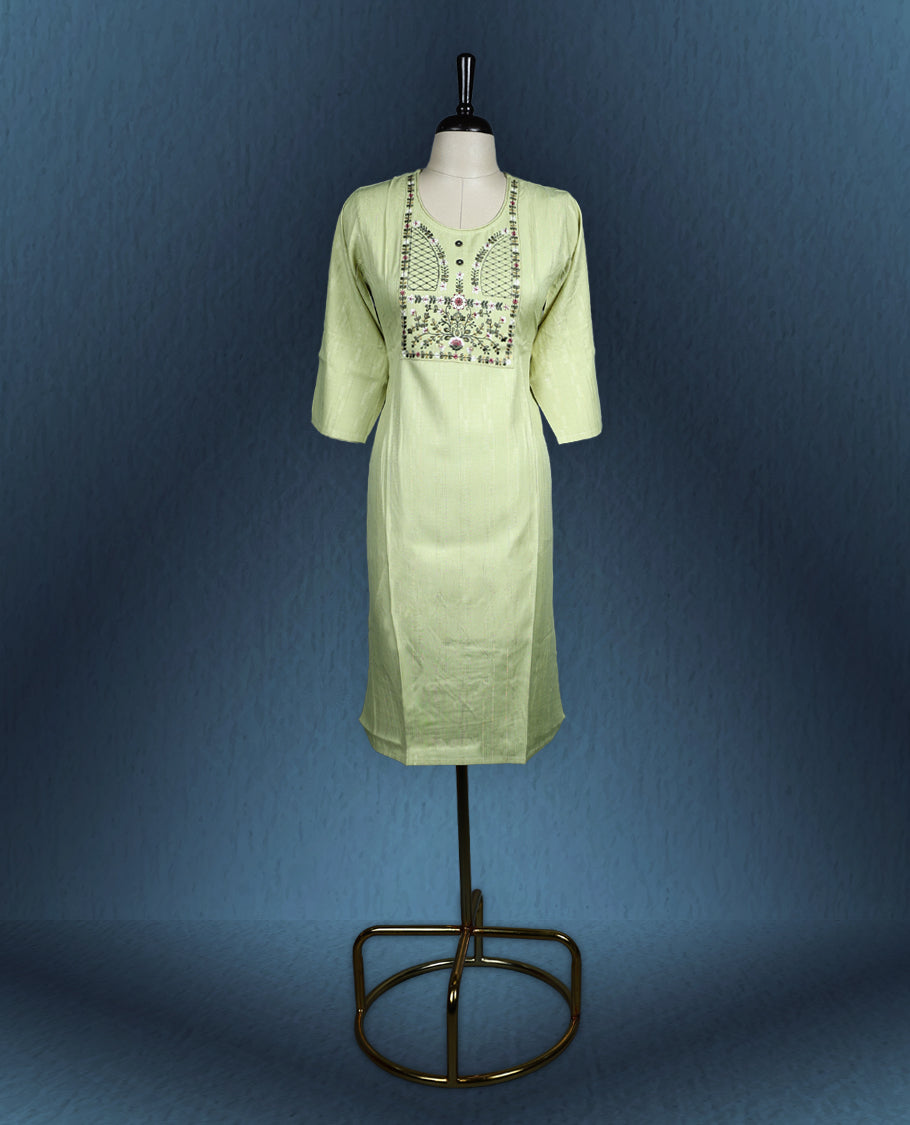 Light green colour kurti with subtle vertical self stripes, highlighted by an intricately embroidered yoke in floral and geometric patterns, featuring a round neckline with button accents and three quarter sleeves.
