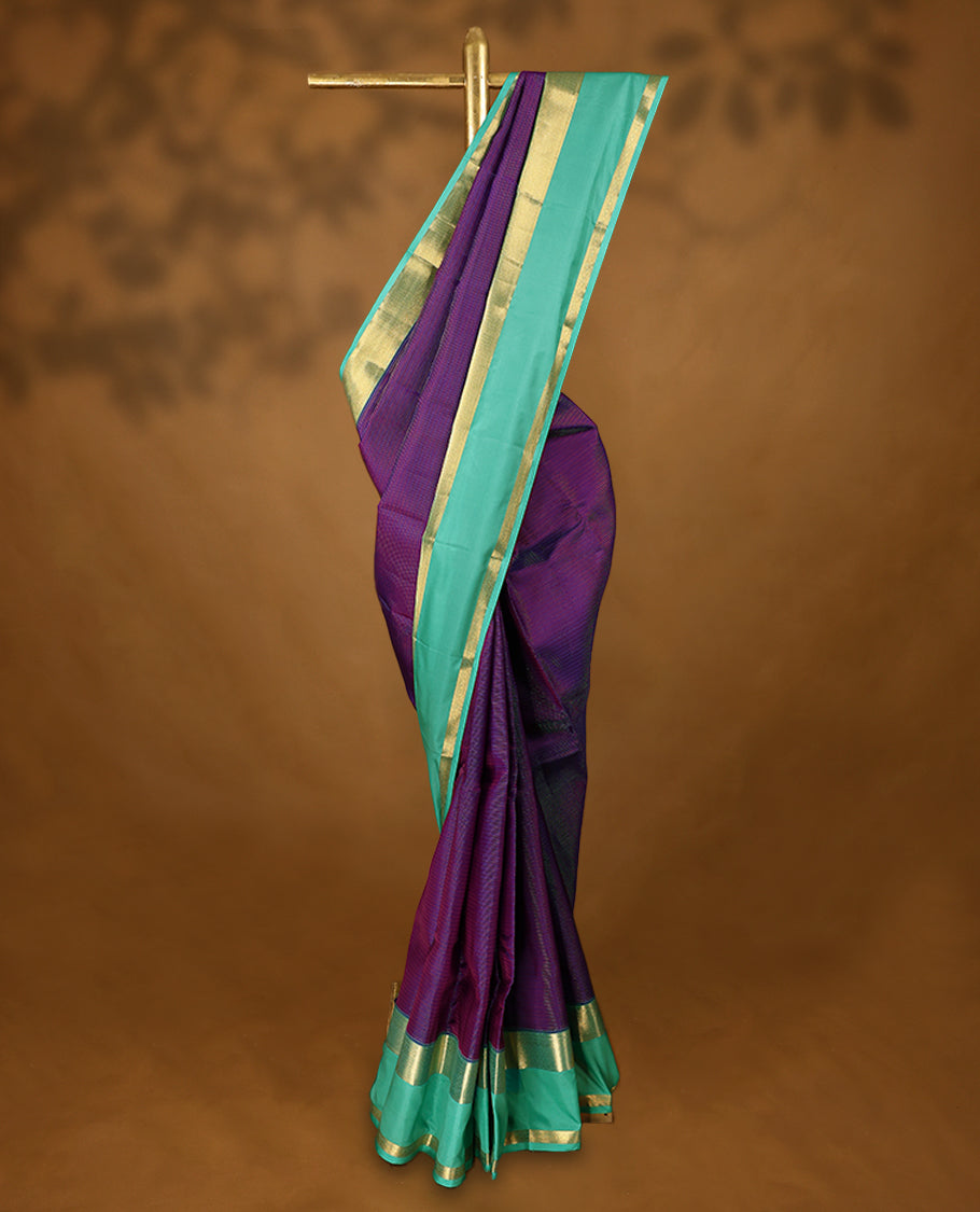 Purple Colour soft silk saree adorned with golden zari stripes on the body, complemented by an aqua colour traditional border and a matching contrast blouse