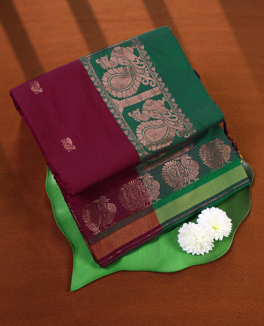 Maroon and Bottle Green Kalyani cotton saree adorned with traditional peacock motifs, enhanced by a rich woven zari border and pallu in green, paired with a matching blouse.