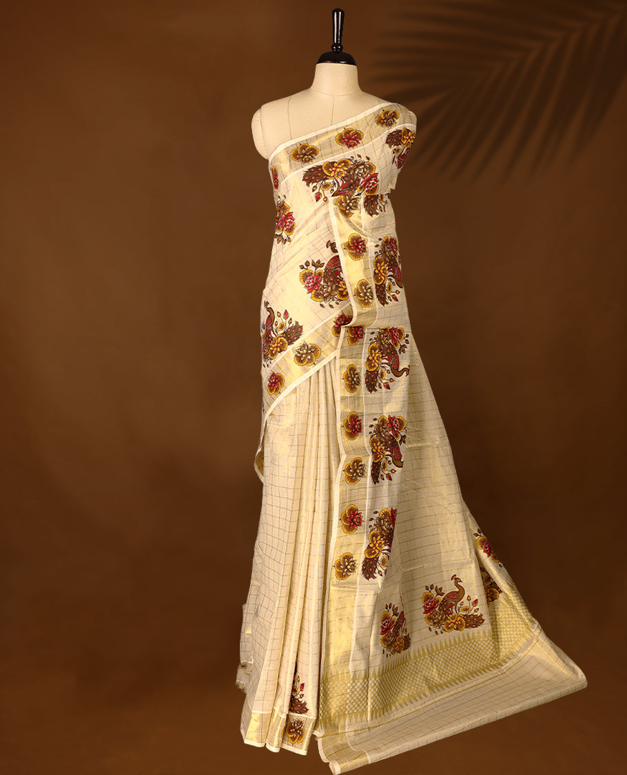Light Gold colour Tissue Kerala saree featuring floral and peacock motifs on the body, golden zari checks, and a beautifully woven border with lotus Printed motifs, paired with a matching blouse perfect for festive occasions.