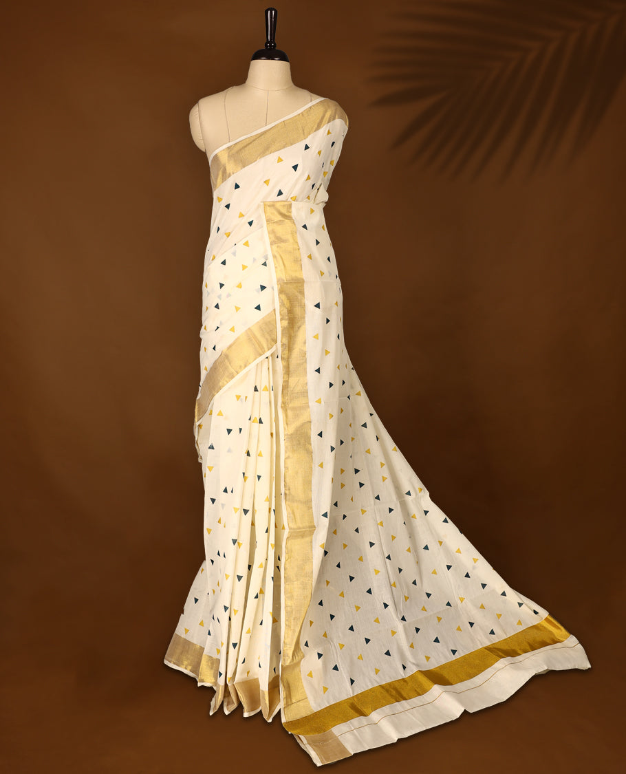 Elegant off white colour cotton Kerala saree featuring Midnight Blue and Gold Triangle prints on the body and traditional golden zari kasavu border offering a classic and graceful look, paired with a matching blouse.