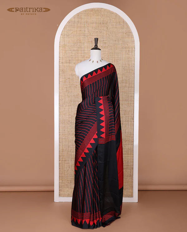 Black sem imodal crepe saree adorned with red vertical line prints, complemented by a temple border and circle butta design on the pallu, paired with a matching printed blouse.