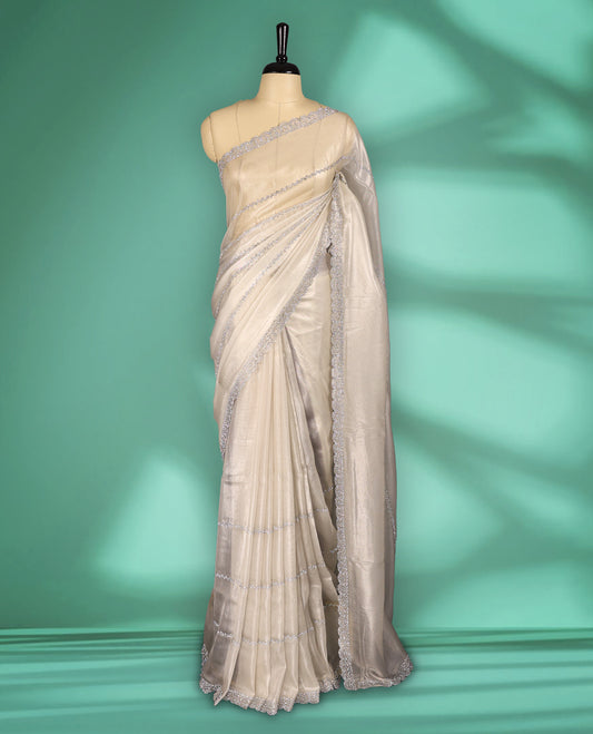 Off white colour net shimmer fancy saree adorned with subtle horizontal White stone patterns on the body, paired with a delicate stone worked border, with matching blouse