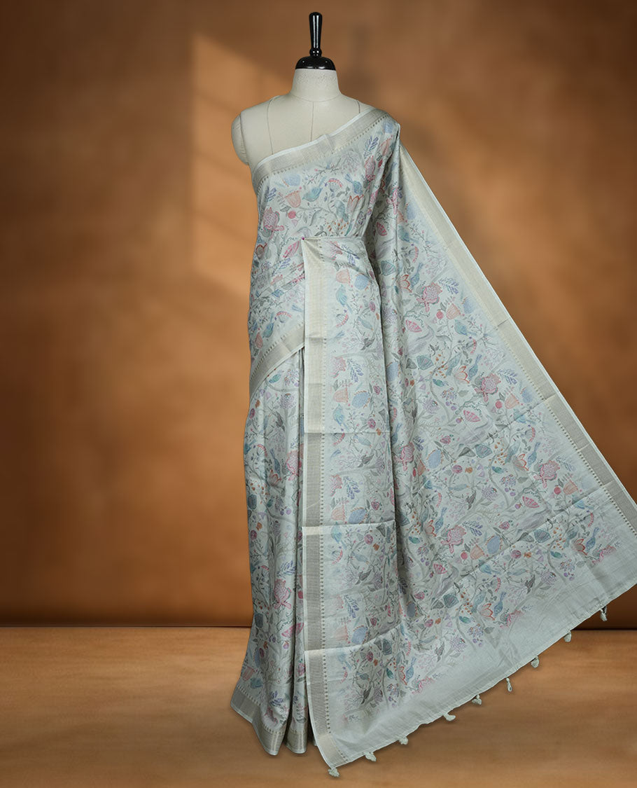 Mint green colour semi tussar silk saree featuring all over floral and leaf motifs on the body with a subtle self border and tasselled pallu, paired with a matching blouse.