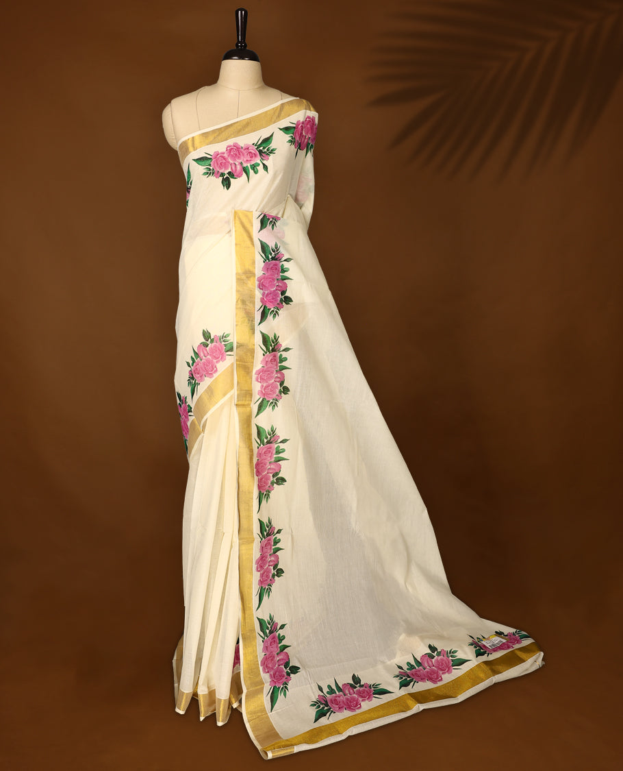 Graceful off white colour Kerala cotton saree with bold pink floral prints and a golden zari border, Lightweight and elegant, it comes with a matching blouse & perfect for festive and semi-formal occasions.