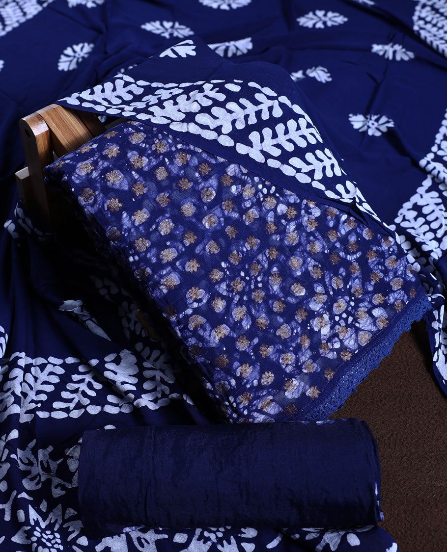 Navy blue colour churidhar material adorned with gold and copper toned floral patterns and bold block designs, paired with a plain matching bottom & Comes with a contrast dupatta featuring bold white leafy block prints.