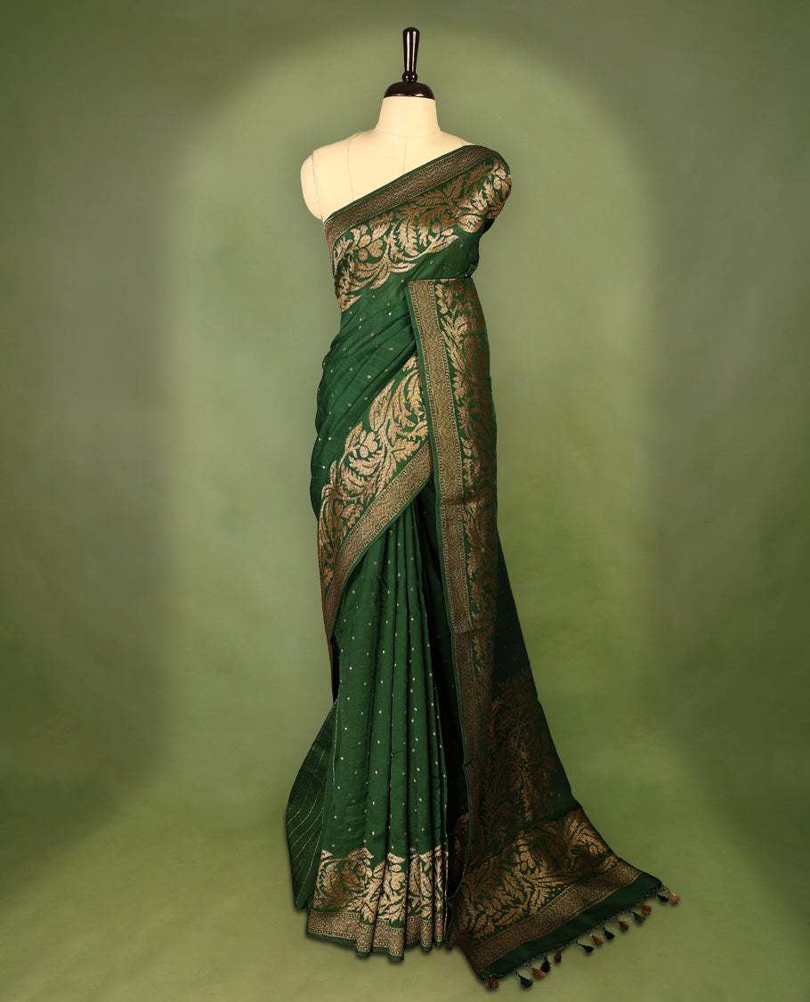 Bottle Green colour Tussar Banaras saree adorned with delicate golden zari motifs on the body, rich floral woven zari border and grand pallu, paired with a matching blouse for an elegant and regal traditional look.
