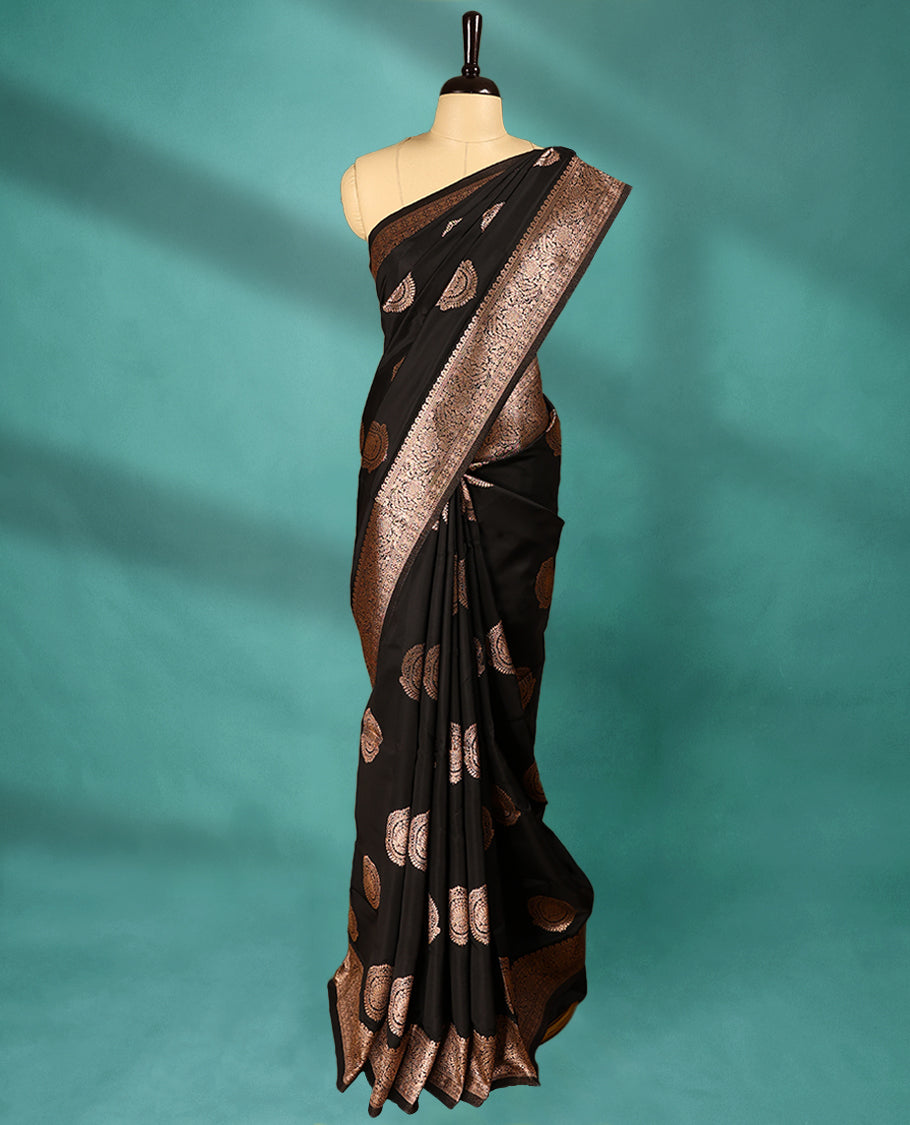 Black coloured semi silk saree featuring a Golden Zari Butta design on the body, paired with a Self coloured border and matching blouse.