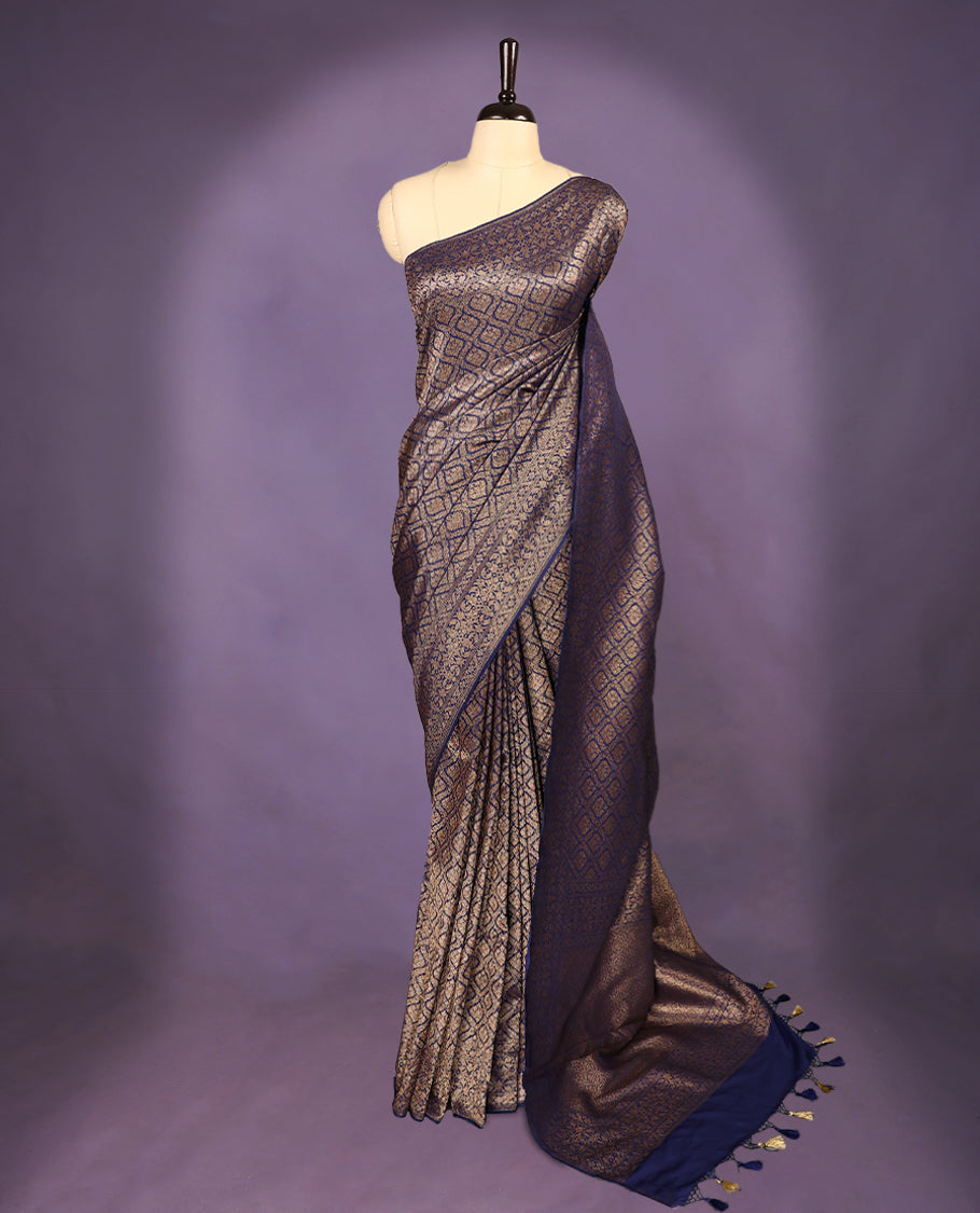 Navy Blue colour semi Banaras Katan saree featuring an antique Gold zari jacquard body, complemented by a self colour traditional border with a floral kodi design, paired with a matching blouse