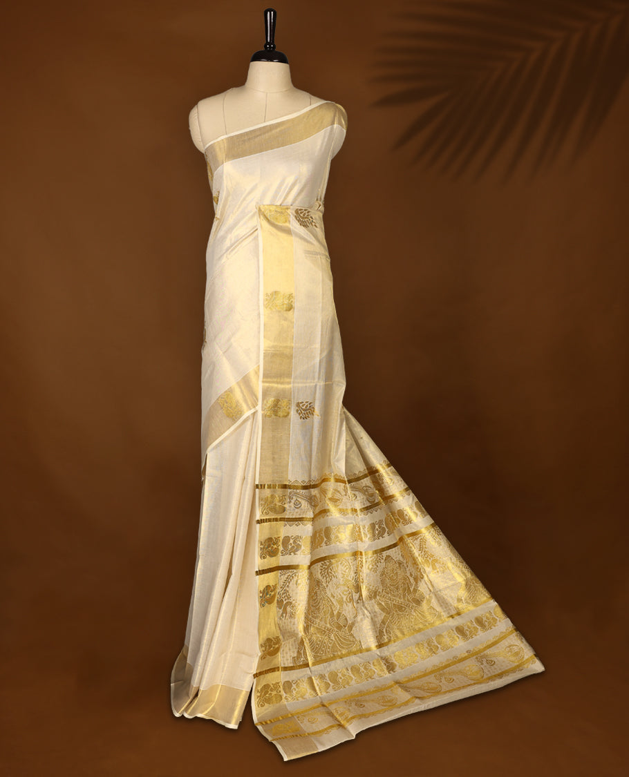 Elegant Light Gold colour Tissue Kerala saree featuring gold zari Leaf motifs on body, traditional golden zari kasavu border with peacock motifs & Rich Pallu paired with a matching blouse.