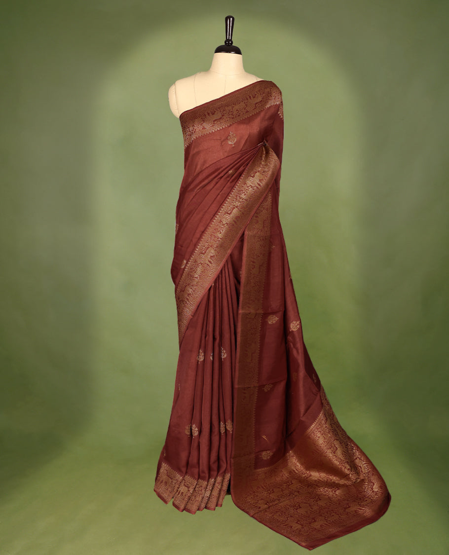 Rust Orange semi-Banaras tussar georgette saree adorned with antique zari butta motifs on the body, accentuated by a beautifully crafted jungle-themed border, and paired with a matching blouse.