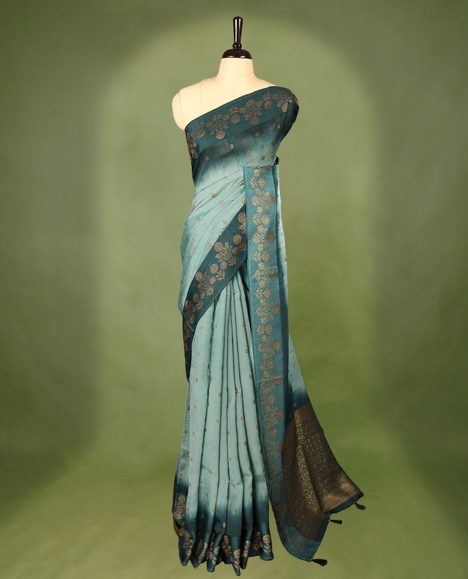Sea green and teal double shade semi Banaras Tussar Georgette saree adorned with elegant antique gold zari floral motifs across the body, featuring a detailed woven border and grand pallu, paired with a matching blouse piece.