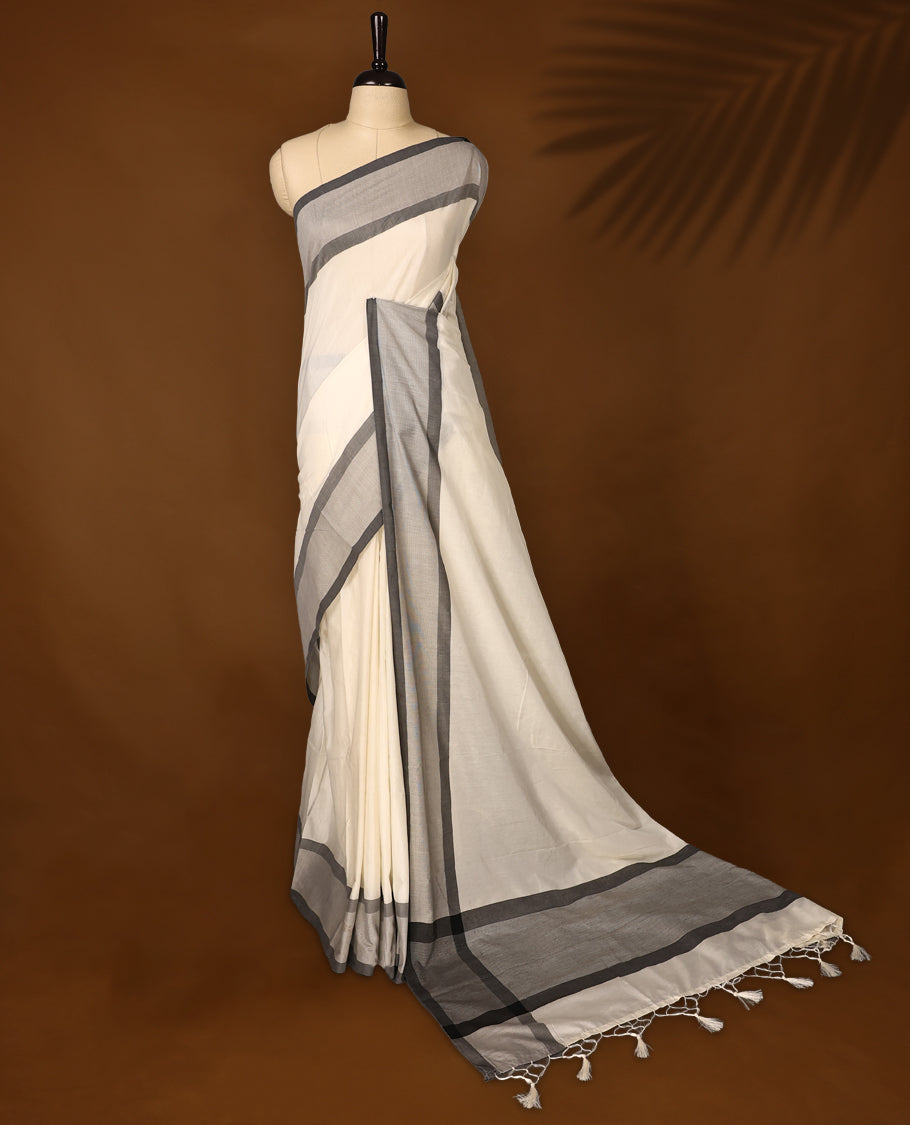 Elegant off white colour Kerala cotton saree with soft grey and charcoal borders, finished with tassel detailing,Lightweight and breathable, it comes with a matching blouse & perfect for everyday, festive, or office wear.