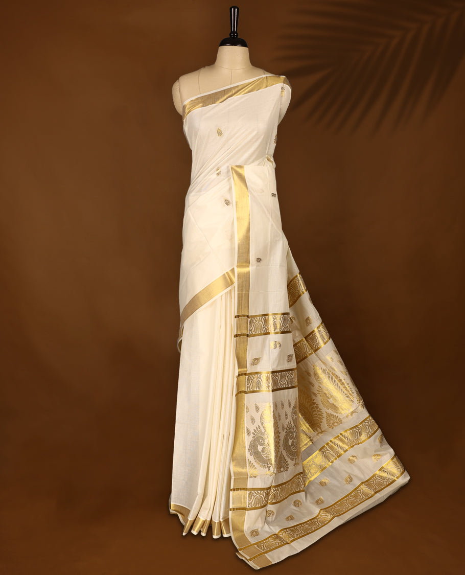Elegant off white colour cotton Kerala saree featuring Gold zari motifs on body, traditional golden zari kasavu border & Rich Pallu offering a classic and graceful look, paired with a matching blouse.