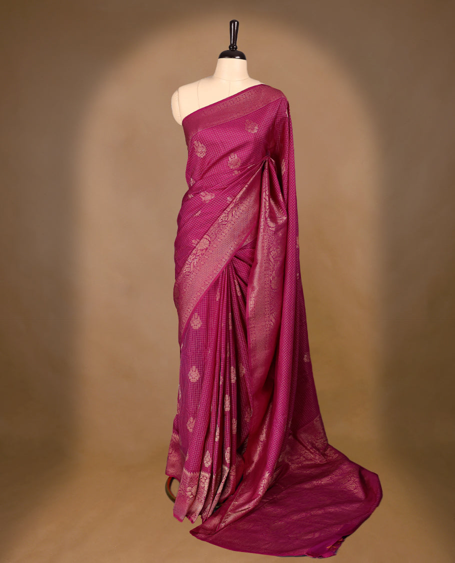 Rani Pink coloured semi Banaras georgette saree featuring golden Zari checks with floral motifs on the body, complemented by a self coloured traditional border with floral kodi design and a matching blouse.
