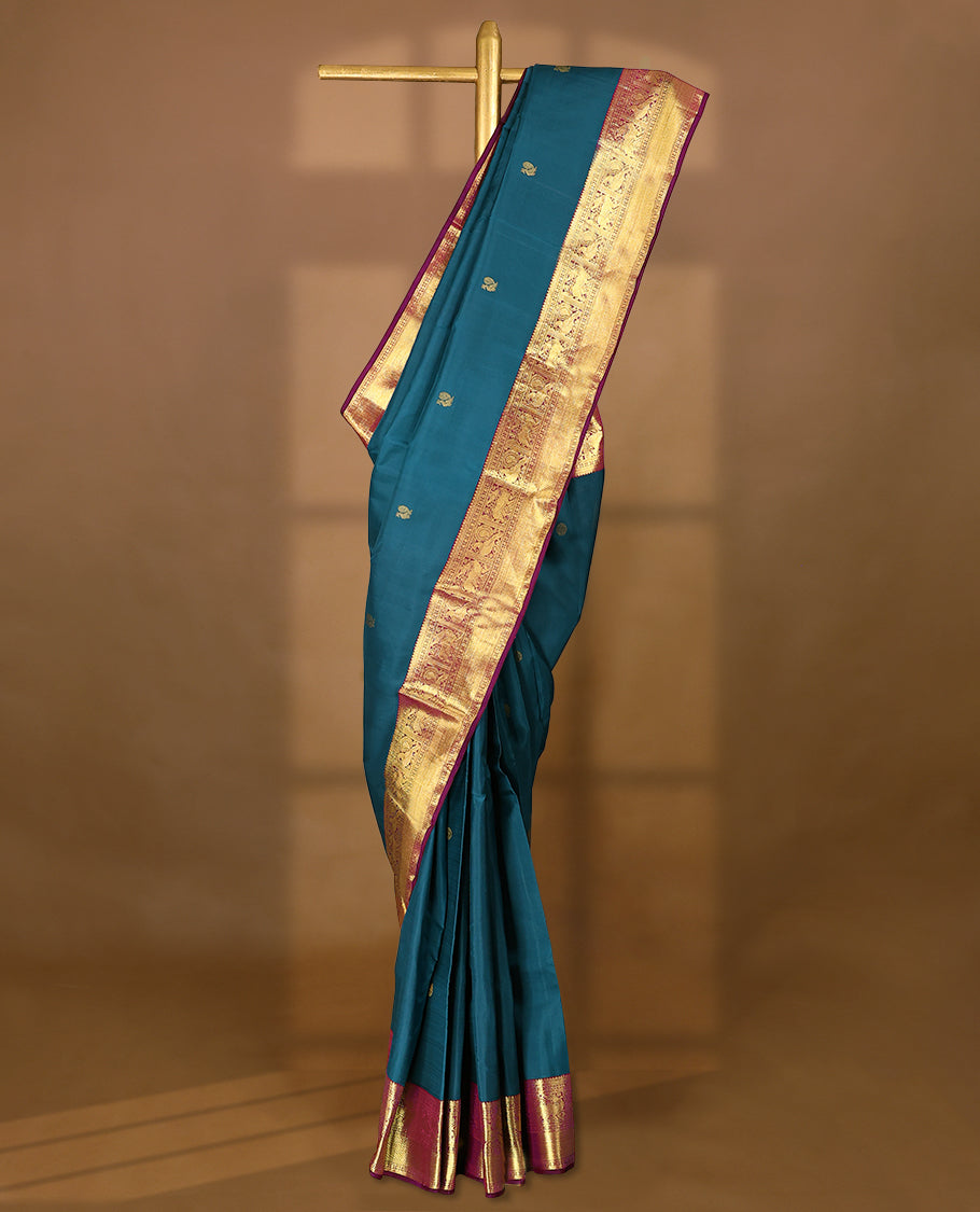 Blue Colour pure traditional Kancheepuram silk saree featuring antique zari peacock and chakkram motifs on the body, complemented by a traditional contrast coloured border and a matching contrast blouse.