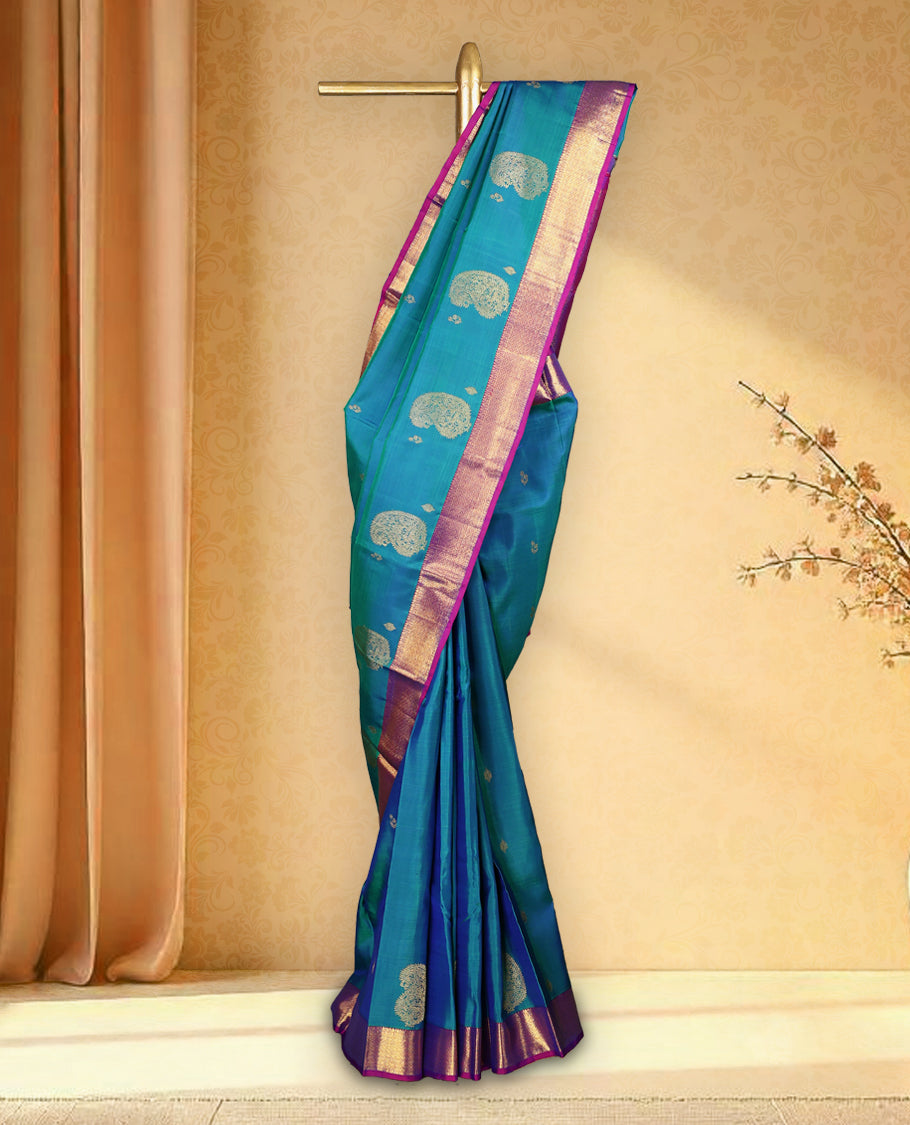 Peacock blue colour pure Kancheepuram saree with gold zari paisley mango motifs on the body traditional border with diamond pattern and purple piping grand pallu paired with matching blouse