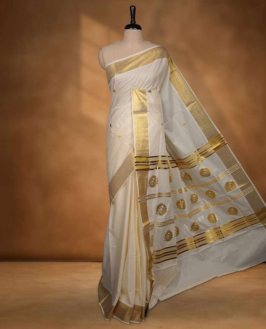 Off-White colour cotton Kerala saree adorned with subtle gold zari buttas, a broad kasavu border, and a richly woven traditional pallu, paired with a matching blouse.