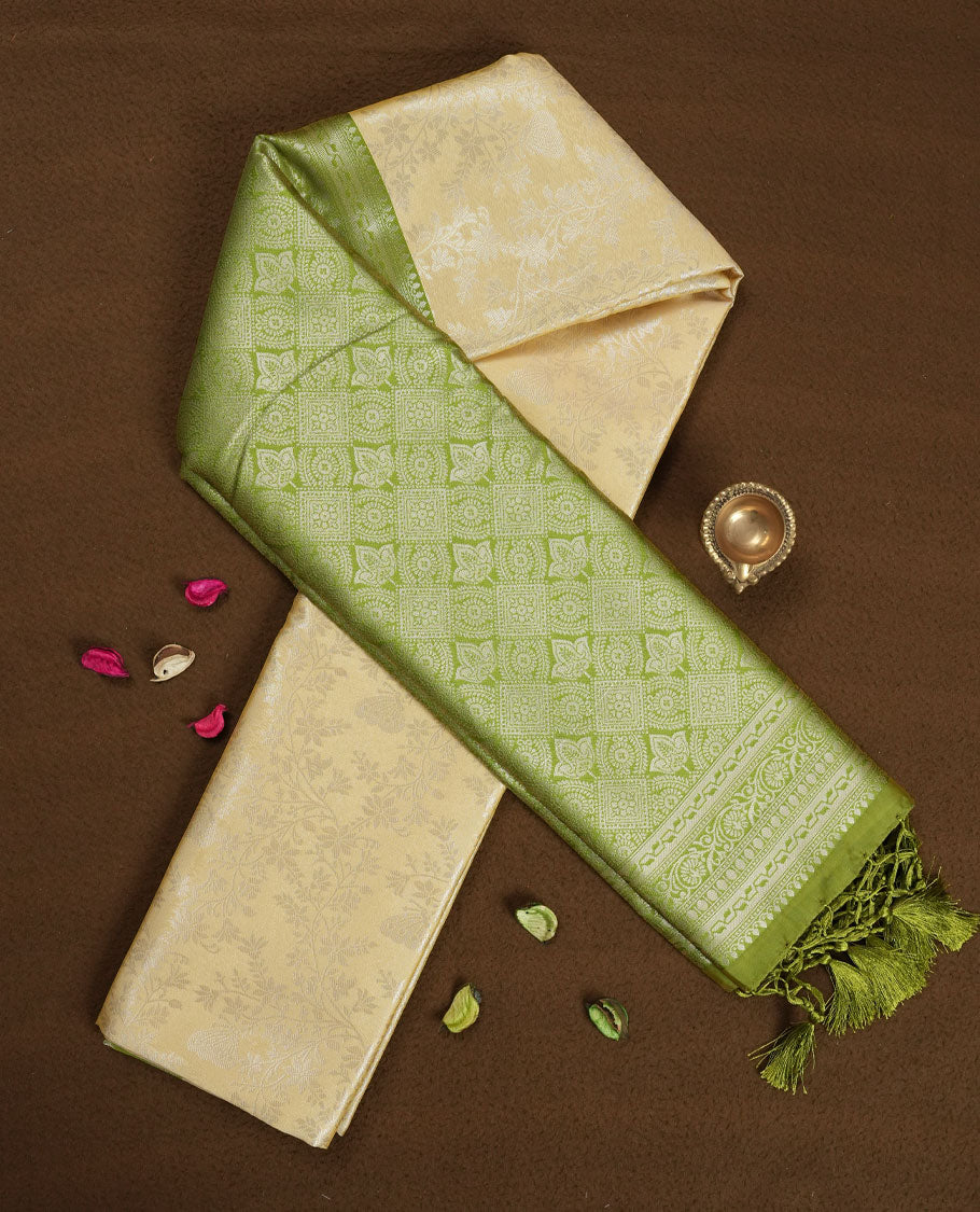 Light cream colour semi silk saree adorned with delicate golden zari buttas across the body, complemented by an elegant olive green pallu and matching border, and paired with a coordinated blouse piece