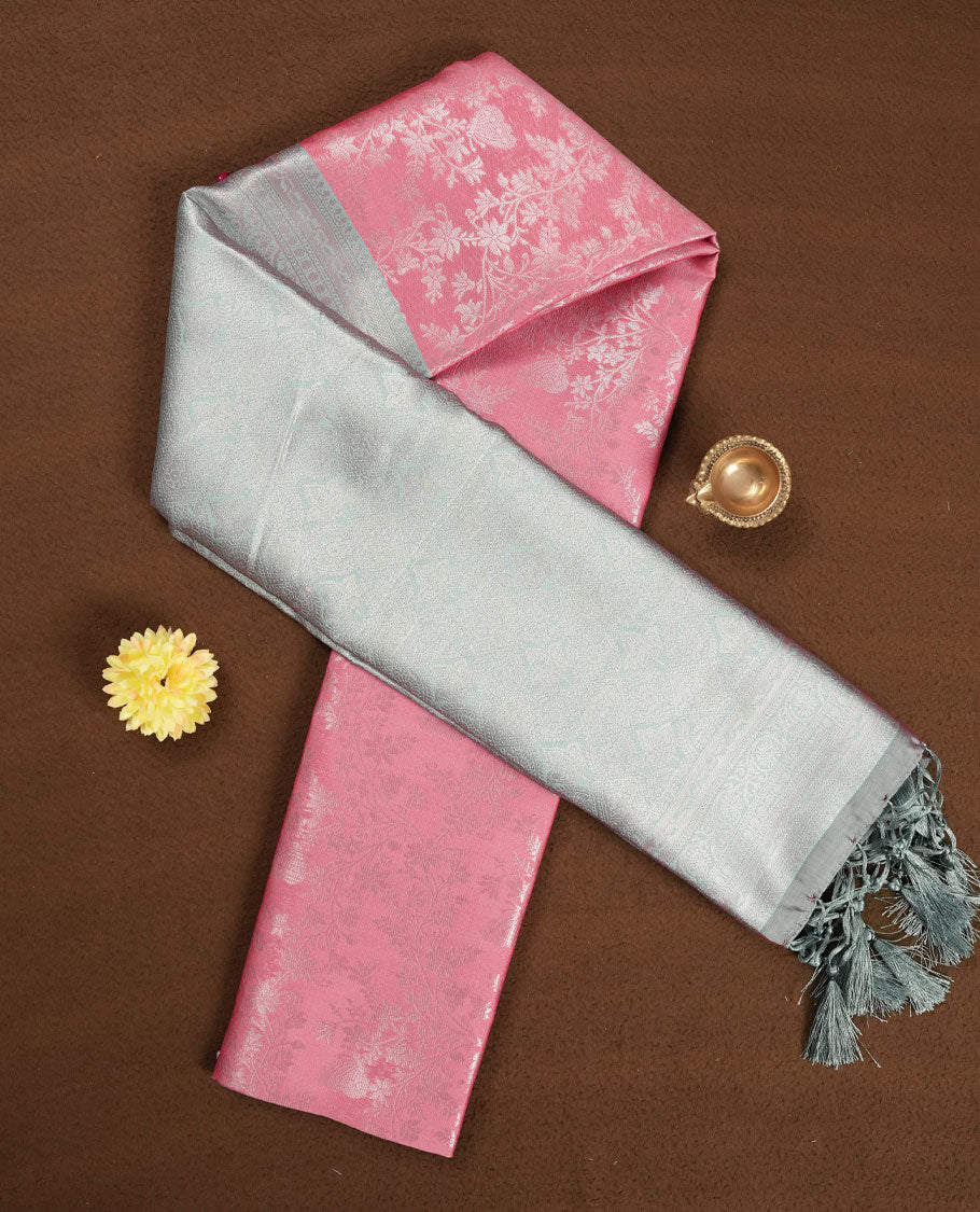 Pink colour semi silk saree adorned with subtle silver floral patterns on the body, complemented by contrasted a silver pallu intricately woven with rich floral patterns border and pallu, and paired with a matching blouse