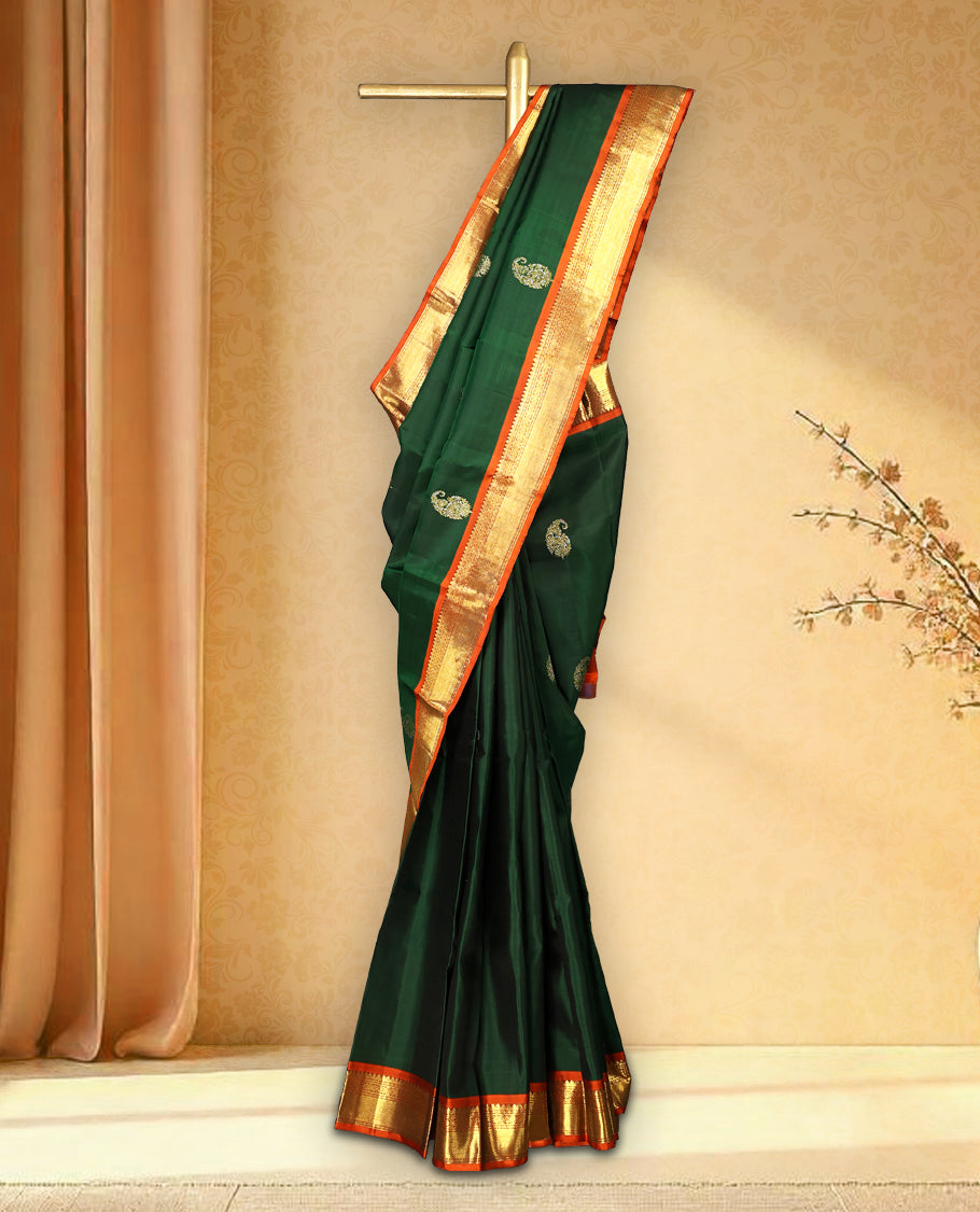 Bottle green colour pure Kancheepuram saree with gold zari traditional paisley motifs on the body contrast traditional border grand pallu with diamond pattern paired with matching blouse