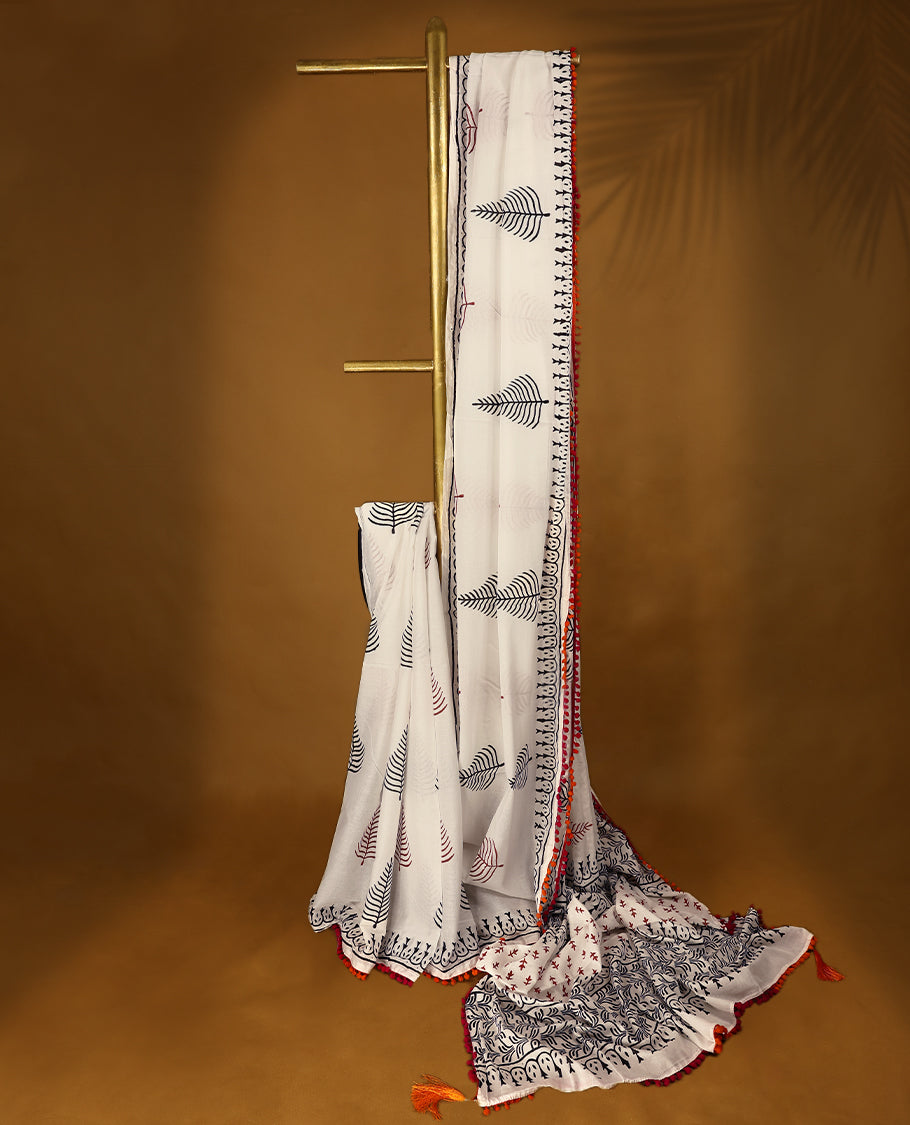 White cotton saree with black handblock prints, a detailed border enhanced with a combination of pink and orange piping, and with contrast blouse.