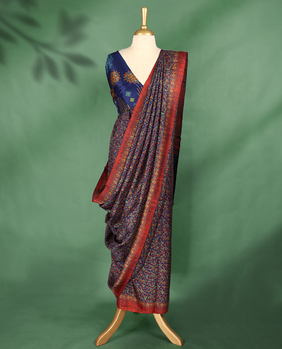 Navy blue colour Manipuri saree adorned with an all over floral pattern in multicolour hues, complemented by a rich rust-red border and matching blouse.