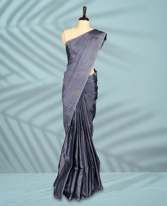 Rich grey toned semi silk saree features golden zari triangle patterns across the body, designed without a border, and comes paired with a matching blouse.