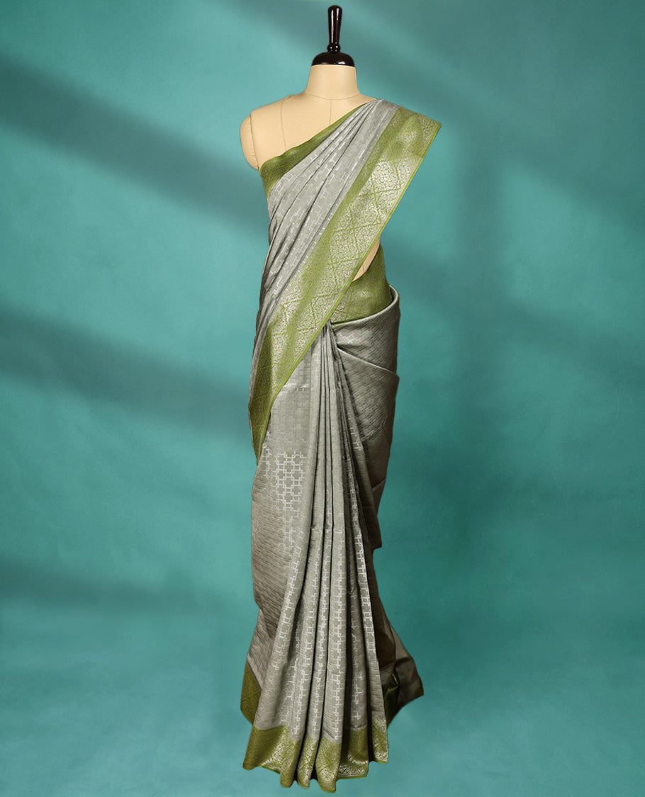 Greenish Grey coloured semi silk saree featuring a Zari design on the body, paired with a Green coloured border and matching blouse.
