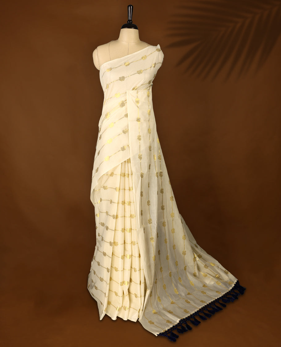 Elegant off white colour cotton Kerala saree featuring a gold Zari stripes with peacock motifs on body, with Blue colour tassels offering a classic and graceful look, paired with a matching blouse.
