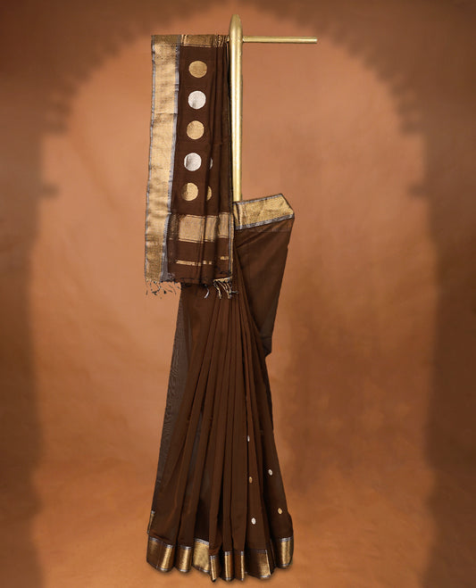 Brown colour Maheshwari Cotton saree featuring Antique Zari bindi Patterns across the entire body, complemented by a traditional Gold Zari border & Pallu, with a matching blouse.