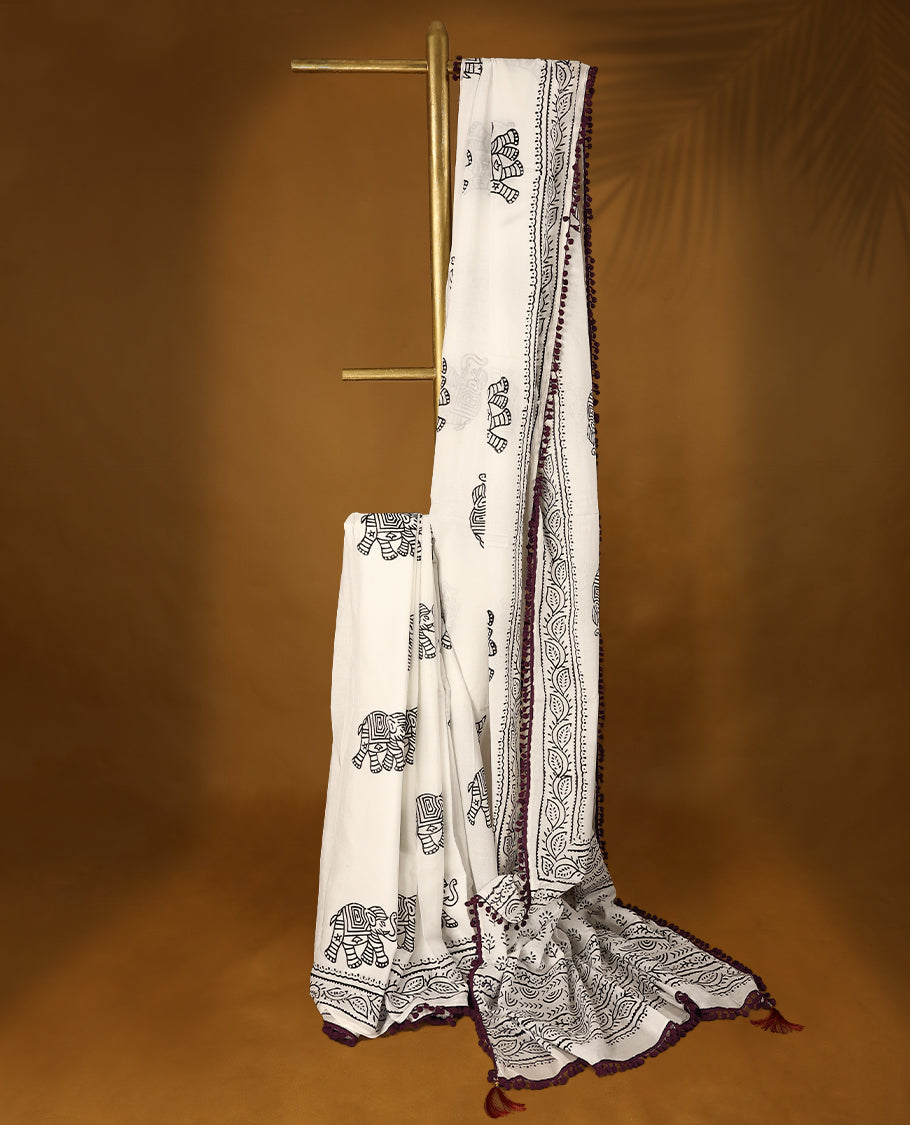 White cotton saree features intricate black elephant handblock prints, a beautifully detailed border with dark grape piping and Self Coloured Blouse