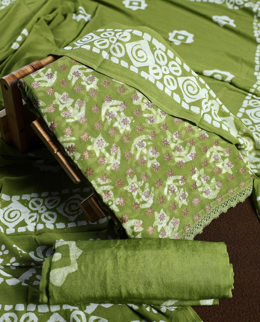 Light green colour churidhar material adorned with gold and copper toned floral patterns and bold block designs, paired with a plain matching bottom and stylish dupatta, perfect for festive evenings and traditional gatherings.