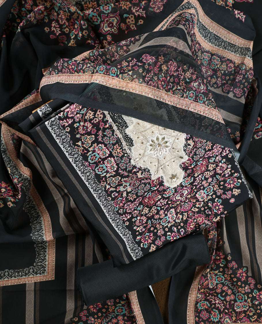 Black colour churidhar set featuring floral prints in pink, teal & beige, paired with plain black bottom and matching dupatta adorned with elegant embroidery.