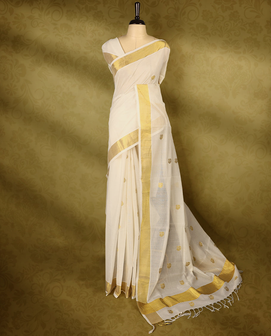 Off white colour pure handloom cotton kerala saree with small gold woven motifs on the body, golden zari border, pallu adorned with gold zari small peacock motifs, with matching blouse