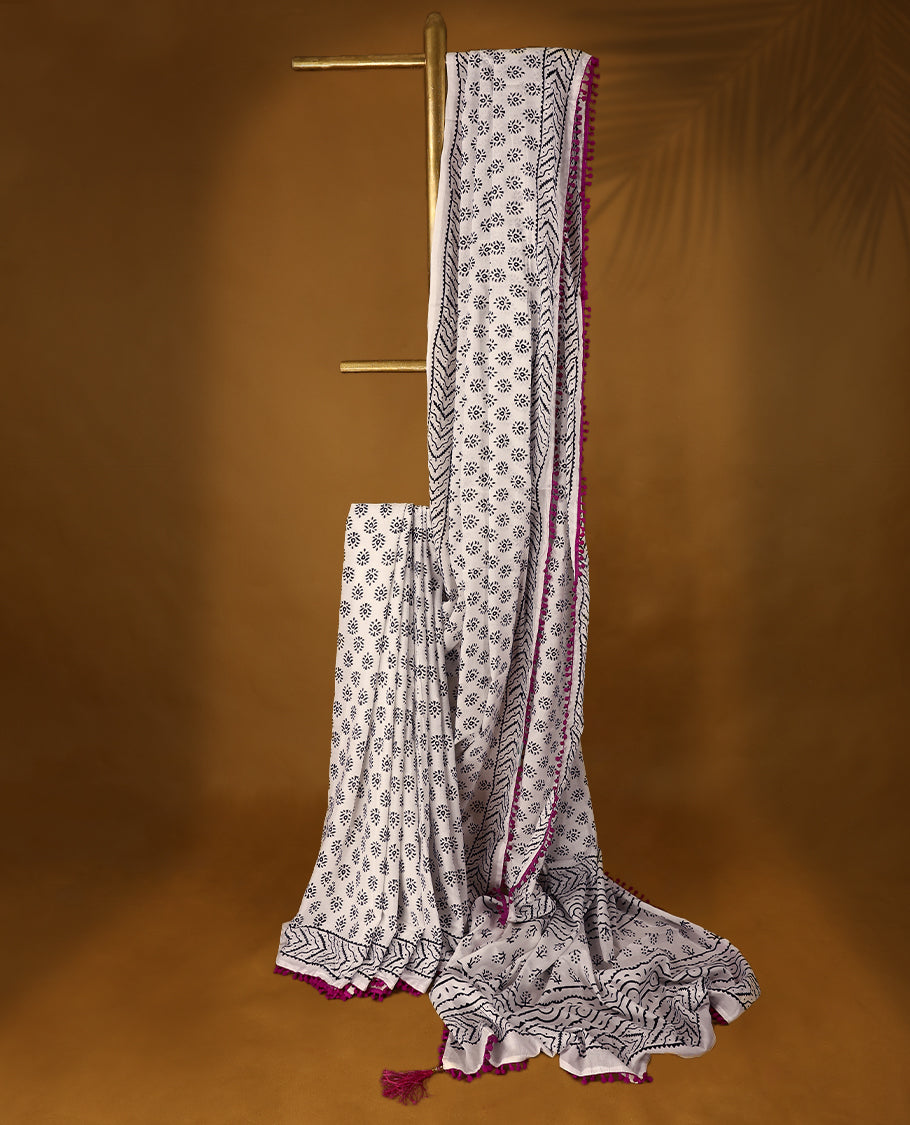 White cotton saree features intricate black handblock prints, a beautifully detailed border with pink piping and Self Coloured Blouse