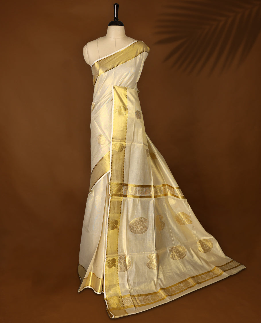 Elegant Light Gold colour Tissue Kerala saree featuring gold zari Chakram motifs on body, traditional golden zari kasavu border & Rich Pallu offering a classic and graceful look, paired with a matching blouse.