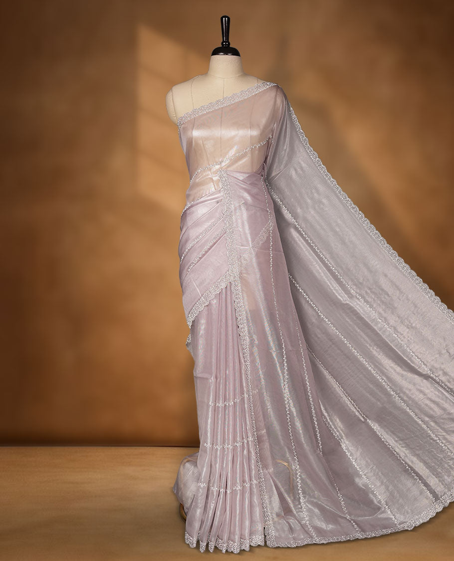 Light lavender colour net shimmer fancy saree adorned with scattered white stone buttas all over the body, paired with a delicate stone worked border and matching blouse.