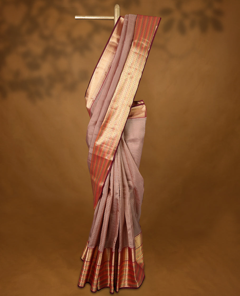 Warm brown Colour soft silk saree with subtle reddish undertones, adorned with golden vertical pinstripes, featuring a contrasting traditional border and paired with a matching blouse.