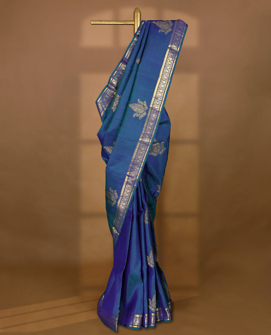 Double-shade peacock-coloured traditional Kancheepuram silk saree adorned with antique floral motifs on the body, featuring a traditional border with floral kodi designs, and paired with a matching blouse