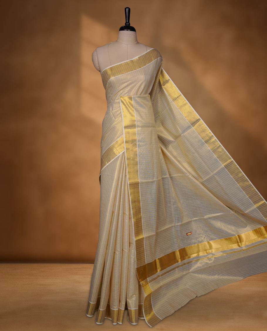 Off-white colour tissue Kerala saree with a timeless gold kasavu border, featuring a subtle striped weave across the body and pallu, paired with a matching blouse.