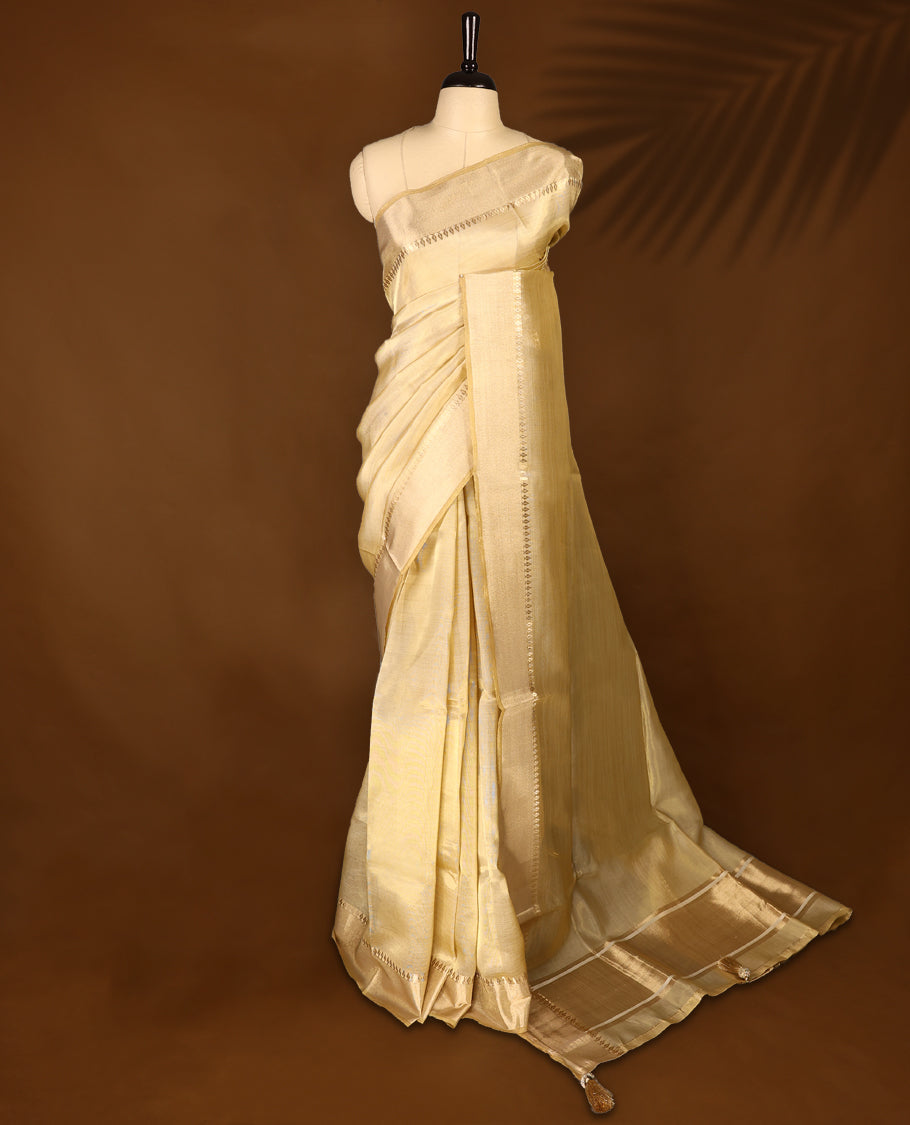 Light gold colour Organza Kerala saree featuring a sheer, luminous body with a soft golden stripes, highlighted by a sleek zari border, Minimal and elegant, it is paired gracefully with a matching blouse piece.
