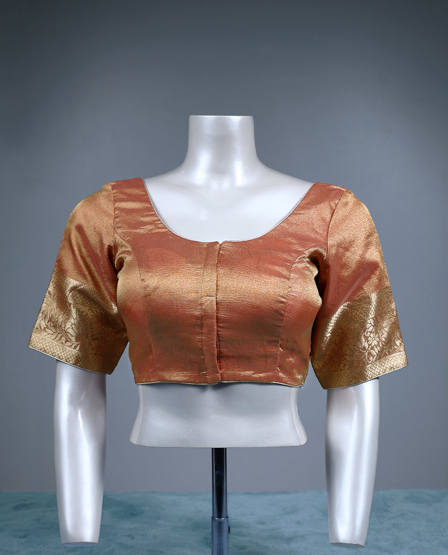 Rust orange colour tissue padded readymade blouse with golden zari weave, complemented by elbow length sleeves featuring intricate floral zari border ideal for traditional silk sarees and festive occasions.