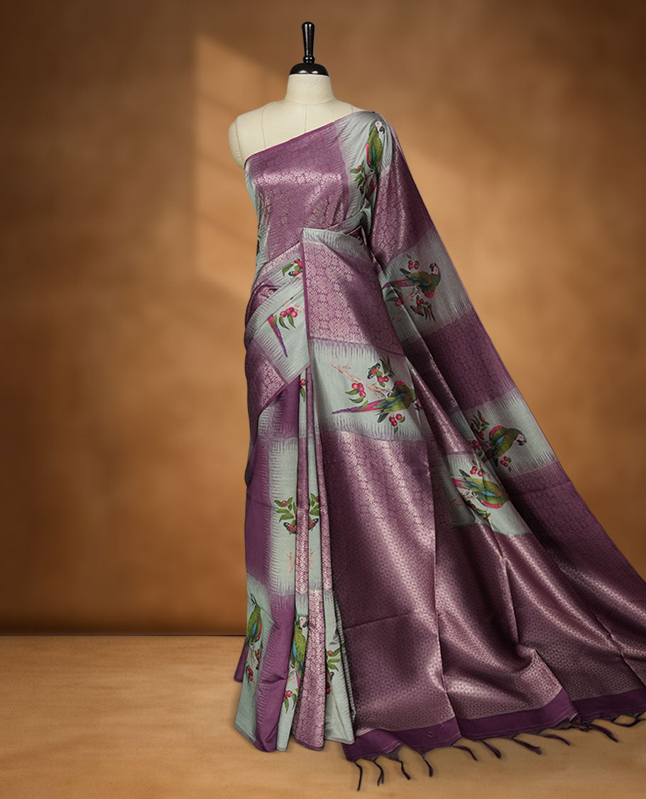 Purple Colour semi tussar Banarasi saree featuring vibrant multi-color floral prints across the body, with shimmering geometric zari patterns, and a matching blouse detailed with silver woven buttas.