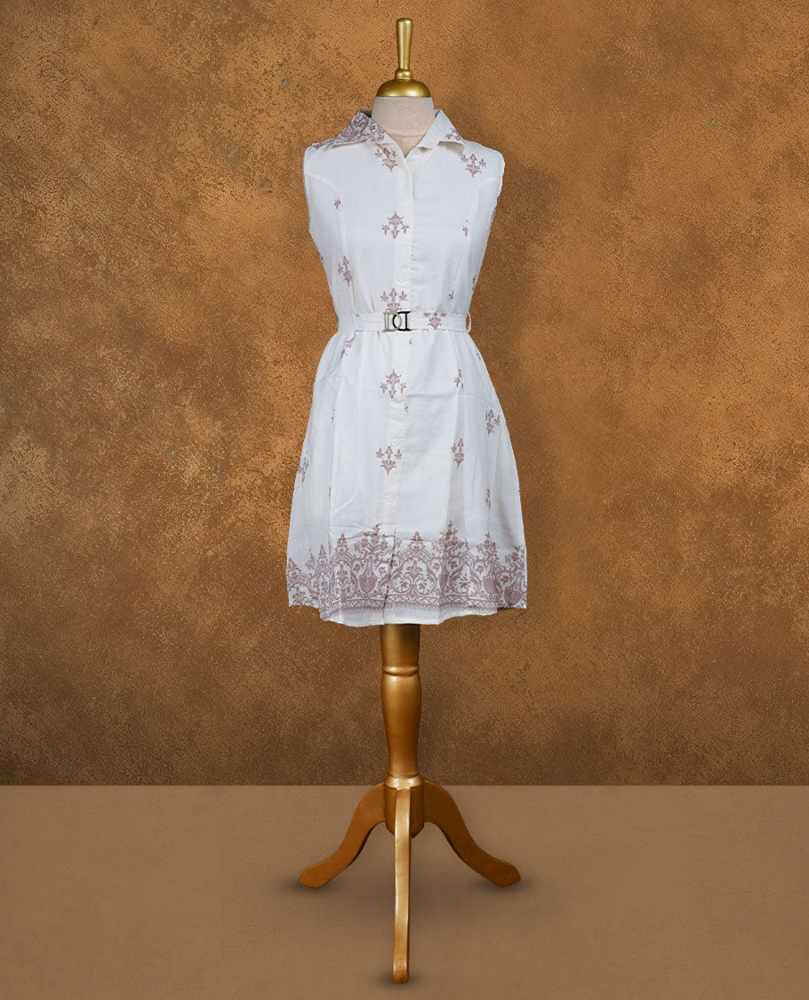 White sleeveless shirt dress with subtle mauve ethnic motifs, front button placket, matching waist belt with metal buckle, and ornate border print at the hem.